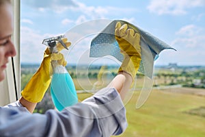Close-up of woman's hands in gloves with rag detergent spray for cleaning windows photo