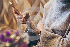 Close-up of woman`s hands holding cell phone while sitting in modern coffee with wood walls.