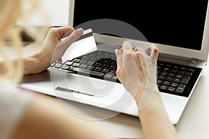 Close-up woman`s hands holding a credit card and using computer keyboard for online shopping.