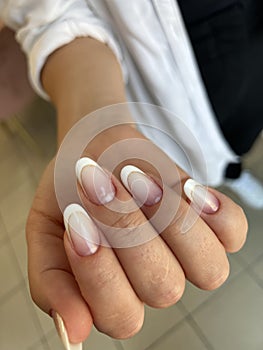 Close-up of a woman's hands with a manicure with pastel-colored French tips