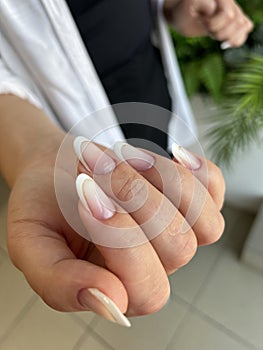 Close-up of a woman's hands with a manicure with pastel-colored French tips
