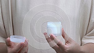 A close-up of woman`s hands opening a jar with cream. and then she closes it back.