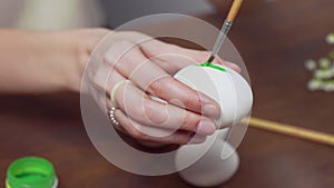 Close-up of a woman's hands painting an easter egg with a paintbrush. Church holiday-Easter