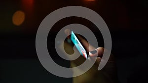 Close-up of woman`s hands performing smartphone at night in a city transport bus