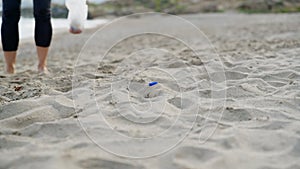 Close-up of a woman's hands picking up plastic trash into a bag on the beach