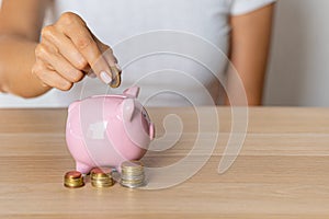Close-up of a woman's hands putting a euro coin in a piggy bank, saving money in a crisis and inflation