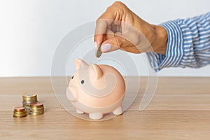 Close-up of a woman's hands putting a euro coin in a piggy bank, saving money in a crisis and inflation