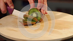Close-up of woman`s hands slicing kiwi on Board.