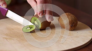 Close-up of woman`s hands slicing kiwi on Board.