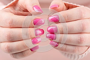 Close-up of a woman& x27;s hands with a stylish pink manicure with glitter.