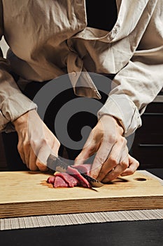 Close-up of woman's hands thinly slicing raw meat for Korean barbecue