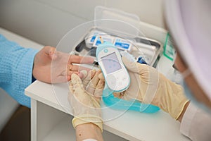 Close up of woman`s hands using lancet on finger to check blood sugar level by glucose meter, Healthcare medical and