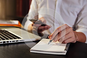 Close up of woman`s hands writing in spiral notepad placed on desk desktop