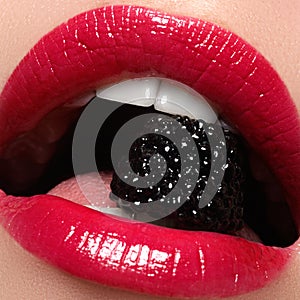 Close-up of woman's lips with bright fashion red glossy makeup. Macro bloody lipgloss make-up. Red sexy lips