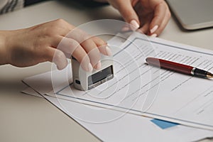 Close up on woman`s notary public hand stamping the document. Notary public concept photo