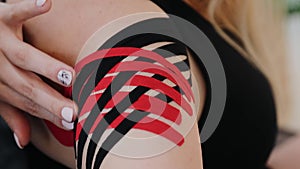 A close-up of woman`s shoulder with applied kinesio tape to demonstrate a stabilization of the shoulder joint