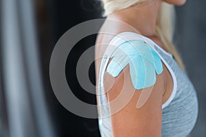 Close-up of a woman`s shoulder and kinesio tape on the shoulder joint