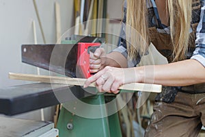 close up of a woman sawing wooden slat