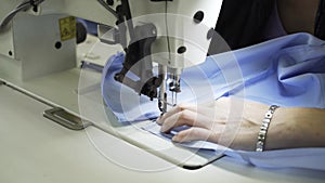 Close up of a woman sewing a shirt at a factory