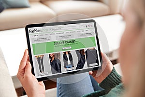 Close Up Of Woman Shopping For Clothes Online At Home Using Digital Tablet App