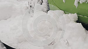 Close-up of a woman with a shovel-cleans snow near the wheels of the car in the back yard.