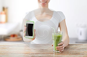 Close up of woman with smartphone and green juice