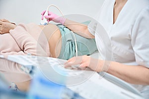 Close-up woman sonographer checking condition of internal organs of woman