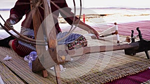 Close-up of a woman spinning thread in a spinning machine which is a tool used to spin cotton into tight threads threads.
