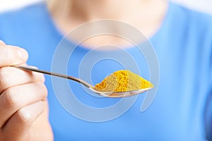 Close Up Of Woman With Spoonful Of Tumeric Powder