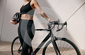 Close up of woman in sportswear is standing with bike and protective helmet before cycling in city