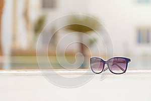 Close-up of woman sunglasses near the pool on a bright sunny day. Resort vacation concept of leisure and lifestyle