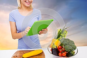 Close up of woman with tablet pc and vegetables