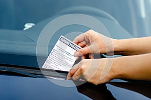 Close-up Of A Woman Taking Parking Ticket On Car`s Windshield