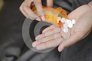 Close up of woman taking in pill she is pours the pills out of the bottle,taking painkiller to reduce sharp ache concept,health
