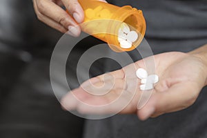 Close up of woman taking in pill she is pours the pills out of the bottle,taking painkiller to reduce sharp ache concept,health