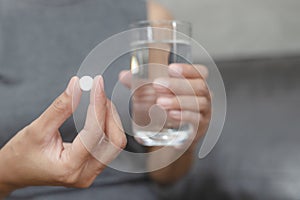 Close up of woman taking in pill she is pours the pills out of the bottle,taking painkiller to reduce sharp ache concept,health