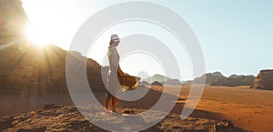 Close up woman tourist in dress stand on cliff barefoot at viewpoint enjoy sunrise on holiday vacation in beautiful Wadi rum