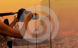 Close up of  woman tourist photographer using a camera takeing a picture of view in the city skyline  with sunset background