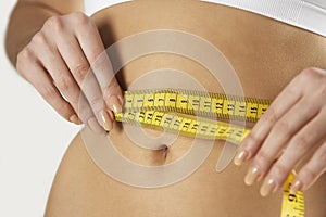 Close-Up Of Woman In Underwear Measuring Waist With Tape photo