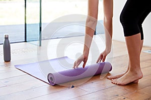 Close Up Of Woman Unrolling Yoga Mat Before Exercise photo