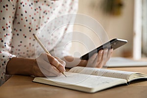 Close up of woman use cellphone write in notebook