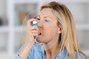 Close-up woman using asthma inhaler in living-room