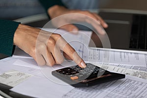 Close up woman using calculator, checking domestic bills, finances