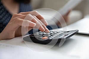 Close up woman using calculator, checking finances, planning budget