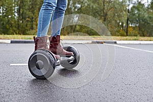 Close up of woman using hoverboard on asphalt road. Feet on electrical scooter outdoor