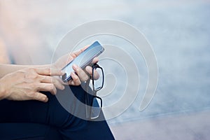 Close up of a woman using mobile smart phone outdoor and glasses