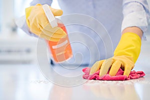 Close Up Of Woman Using Spray Polish To Clean Kitchen Surface