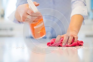 Close Up Of Woman Using Spray Polish To Clean Kitchen Surface
