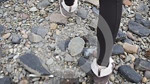 Close up of a Woman Walking with Brown Shoes and Black Trousers over Coastal Stones