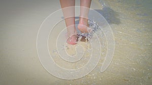 Close up of a woman walking on exotic white sandy beach.